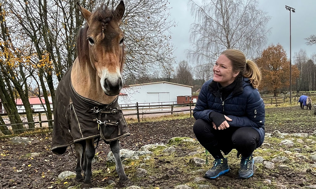 Kvinna står brevid en häst